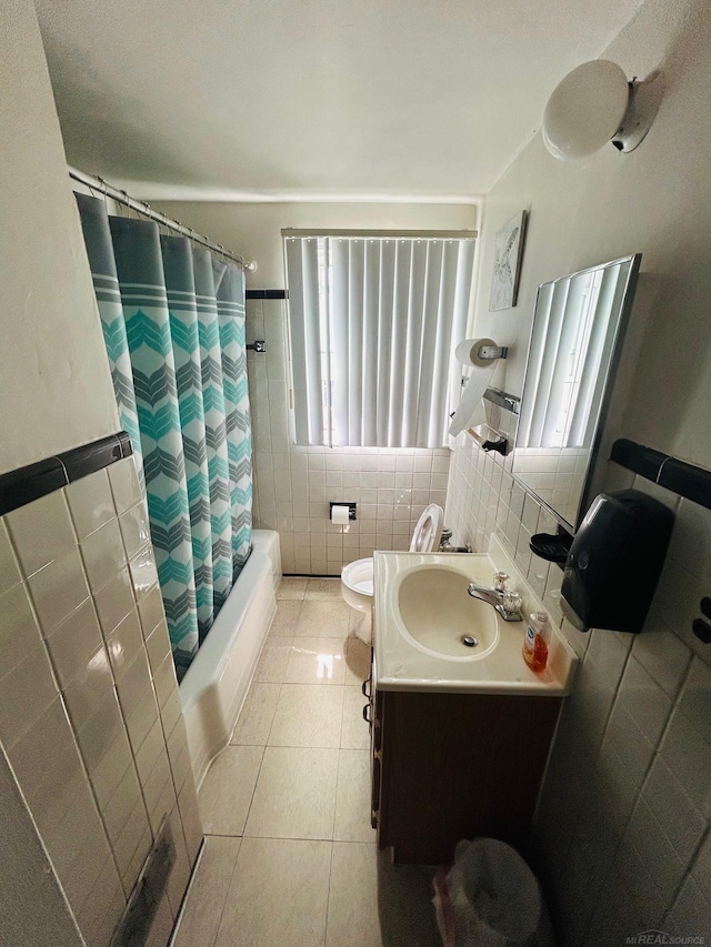 bathroom with vanity, toilet, tile patterned floors, shower / bathtub combination with curtain, and tile walls