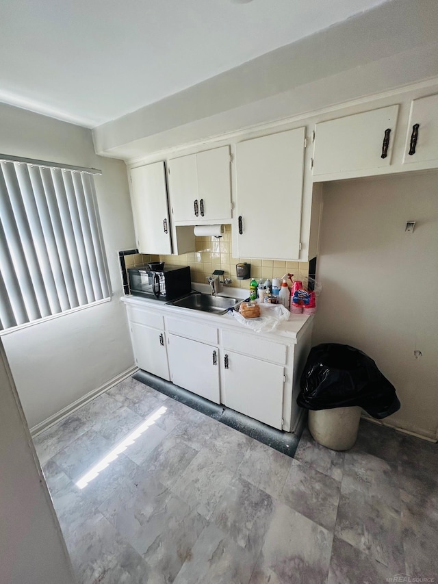 kitchen featuring a sink, light countertops, decorative backsplash, and white cabinetry