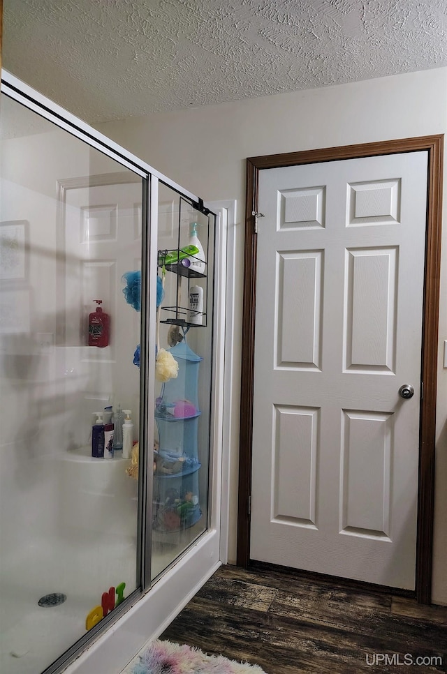 bathroom with a shower stall, wood finished floors, and a textured ceiling