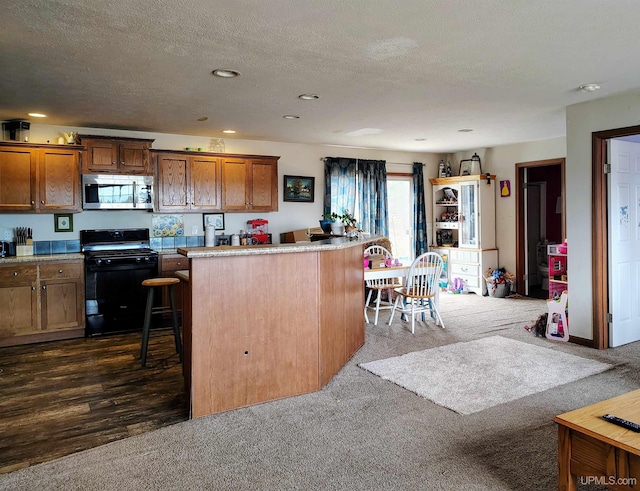 kitchen with stainless steel microwave, brown cabinetry, a center island, dark carpet, and gas stove