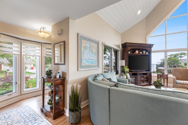 living area featuring light wood-style flooring, lofted ceiling, and baseboards