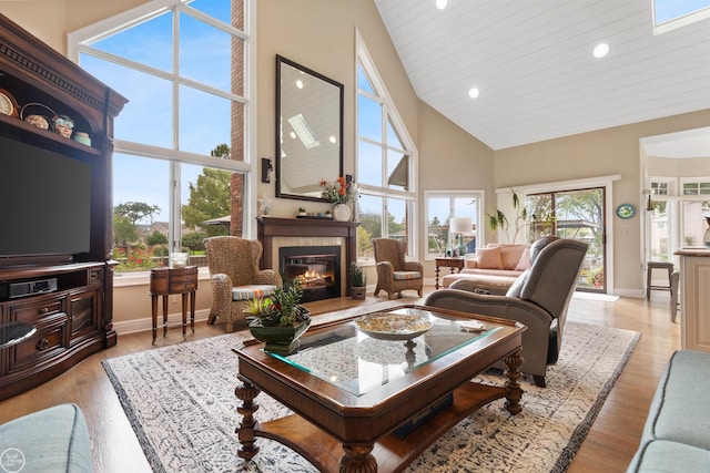 living area with a tiled fireplace, recessed lighting, high vaulted ceiling, and baseboards