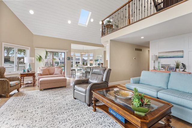 living room featuring a skylight, high vaulted ceiling, a wealth of natural light, and visible vents