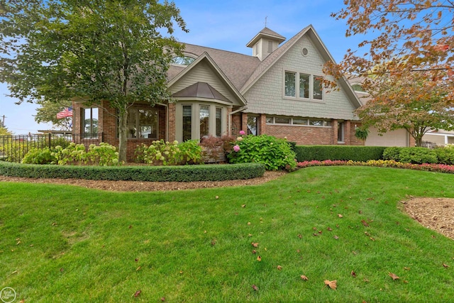 view of front of home featuring fence, roof with shingles, a front lawn, and brick siding