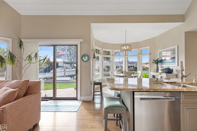 kitchen with dishwasher, a sink, baseboards, light wood-type flooring, and a notable chandelier