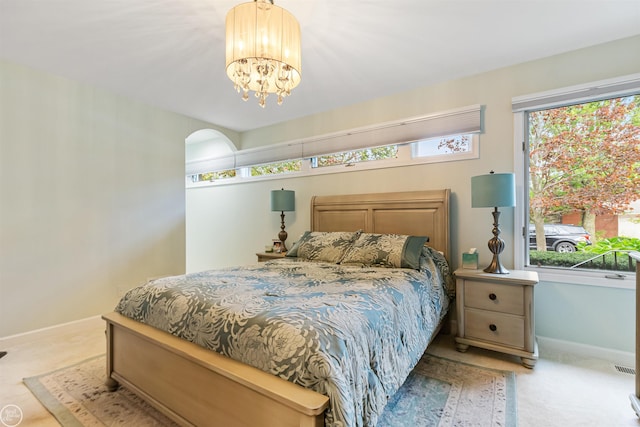 carpeted bedroom with a notable chandelier and baseboards