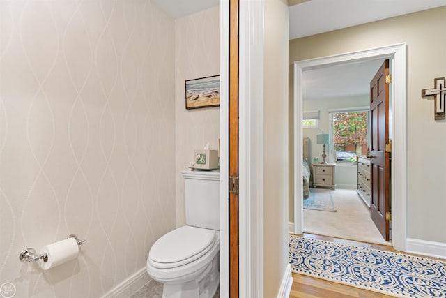 bathroom with wood finished floors, toilet, and baseboards