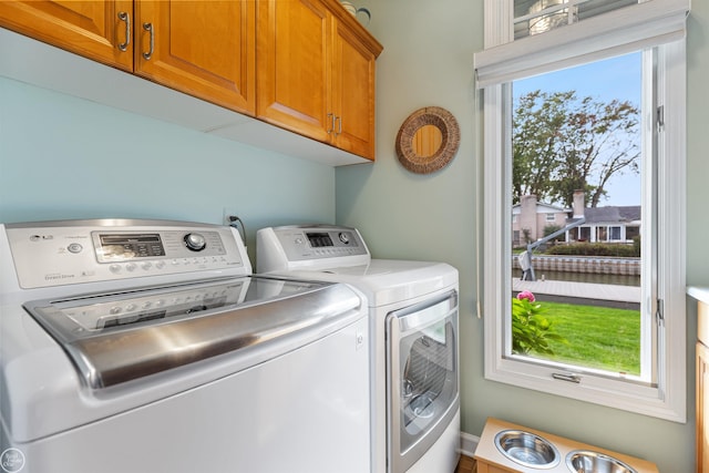 clothes washing area featuring cabinet space and washing machine and dryer