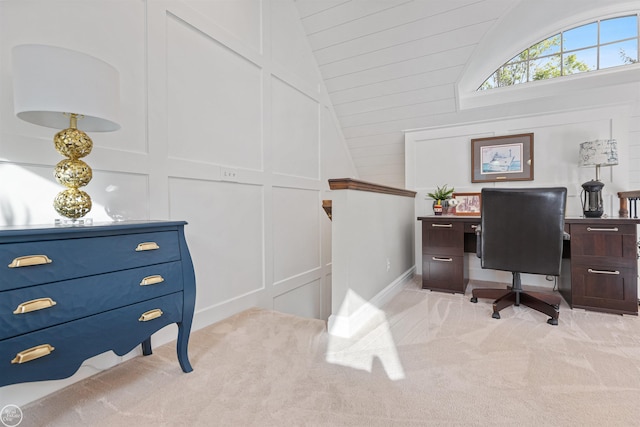 office with a decorative wall, vaulted ceiling, and light colored carpet