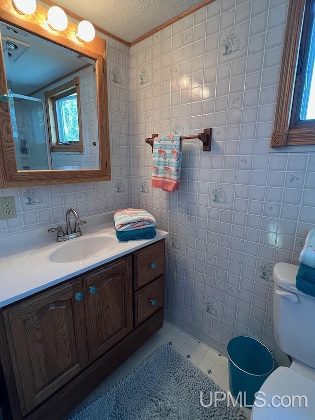 full bath with tile patterned floors, tile walls, toilet, vanity, and crown molding