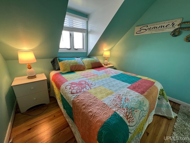 bedroom featuring lofted ceiling, baseboards, and wood-type flooring