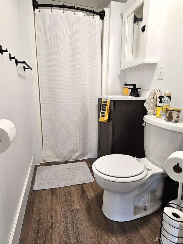 bathroom with baseboards, curtained shower, wood finished floors, and toilet