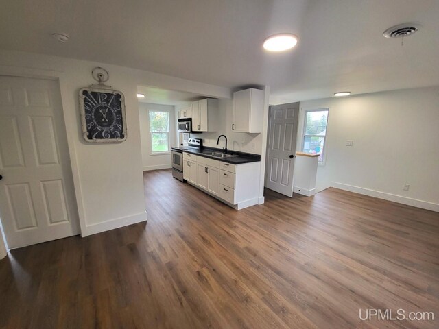 kitchen featuring dark countertops, white cabinets, appliances with stainless steel finishes, and a healthy amount of sunlight