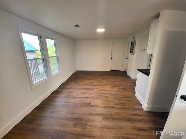 unfurnished dining area featuring baseboards, recessed lighting, and dark wood-type flooring