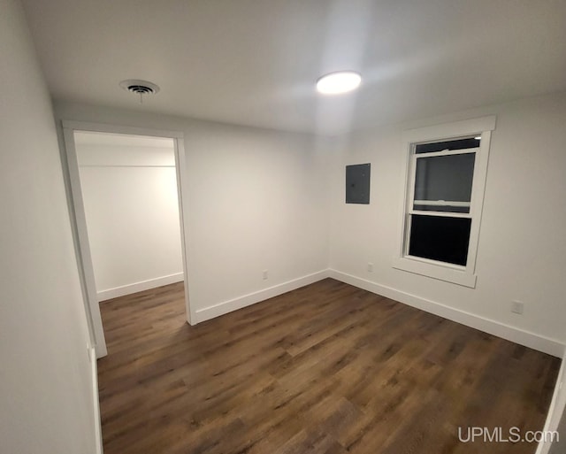 empty room with baseboards, visible vents, and dark wood finished floors