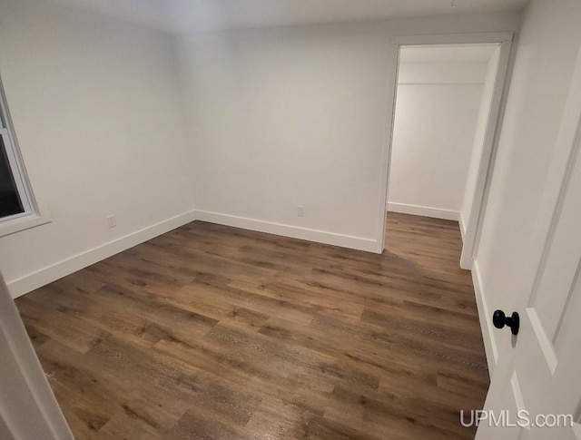 unfurnished room with dark wood finished floors and baseboards