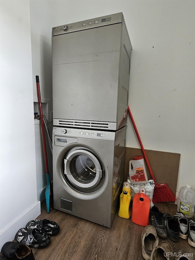 laundry room with stacked washer and dryer, wood finished floors, and laundry area