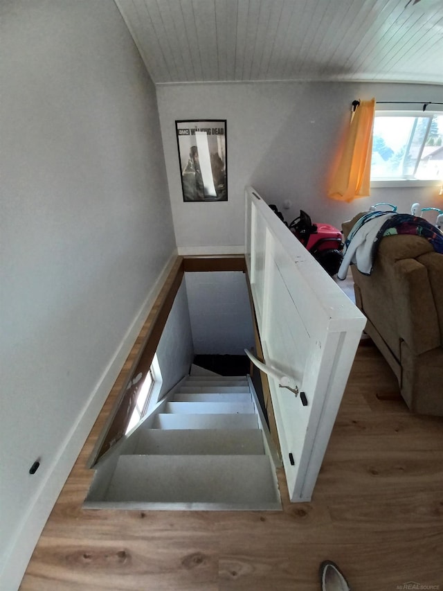 stairway featuring baseboards, wood finished floors, and wood ceiling