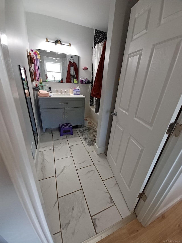 full bath featuring baseboards, shower / bath combo, vanity, and marble finish floor