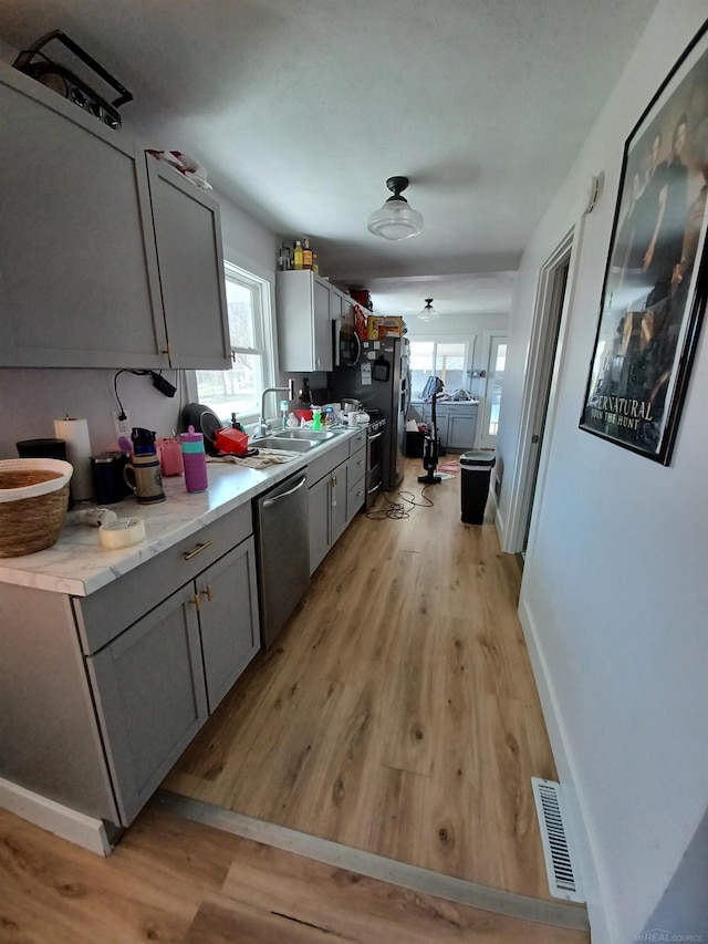 kitchen featuring appliances with stainless steel finishes, light wood-style floors, visible vents, and a sink