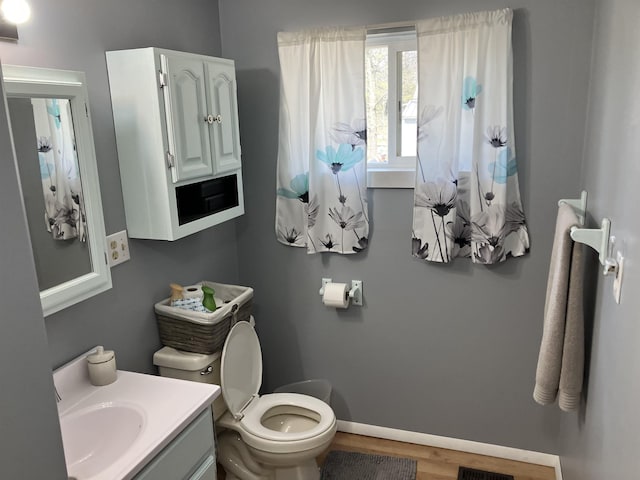 bathroom with toilet, wood finished floors, vanity, and baseboards