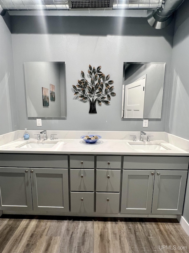 full bath featuring wood finished floors, double vanity, and a sink