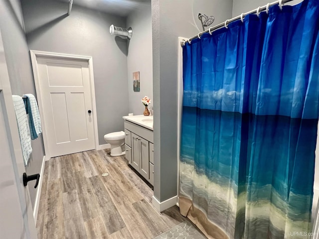 bathroom with curtained shower, wood finished floors, toilet, and vanity