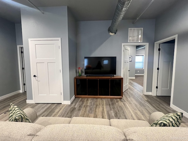 living room with baseboards, visible vents, and wood finished floors