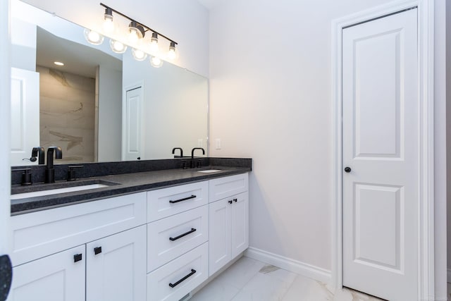 bathroom with double vanity, baseboards, marble finish floor, and a sink