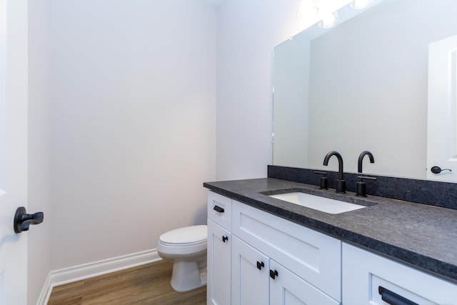 bathroom featuring toilet, wood finished floors, vanity, and baseboards