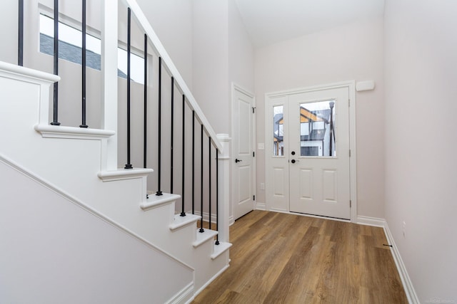 entryway with stairway, wood finished floors, and baseboards