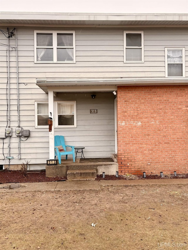 back of property with a porch and brick siding