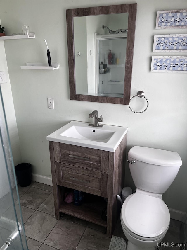bathroom with a stall shower, baseboards, toilet, vanity, and marble finish floor