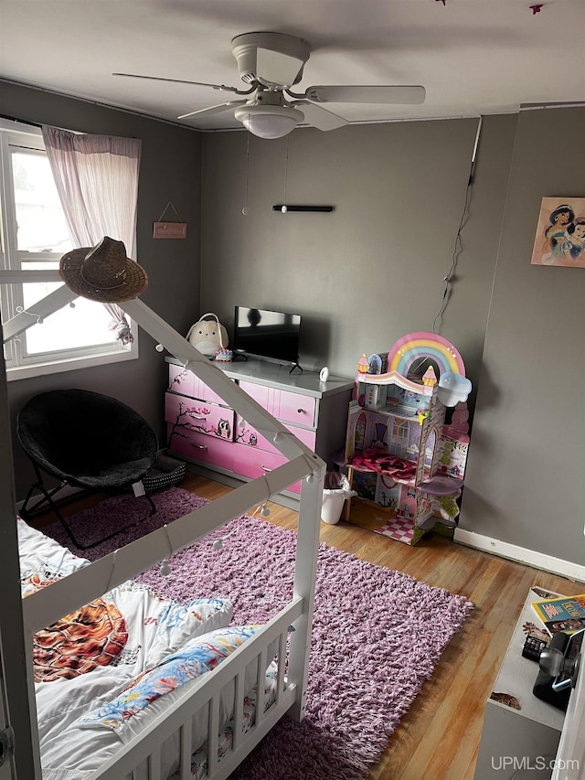 bedroom with ceiling fan, wood finished floors, and baseboards