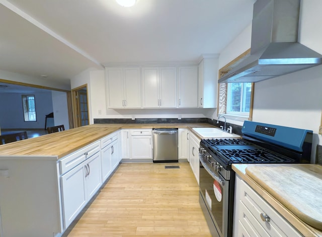 4358 Lakeshore Rd, Lexington, MI 48450 - kitchen featuring wall chimney range hood, light wood-style flooring, a sink, appliances with stainless steel finishes, and wooden counters