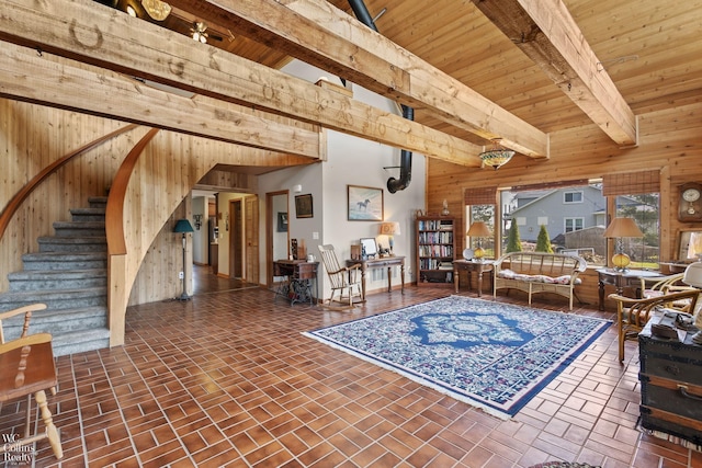 living room featuring stairs, wood ceiling, beamed ceiling, brick floor, and wood walls