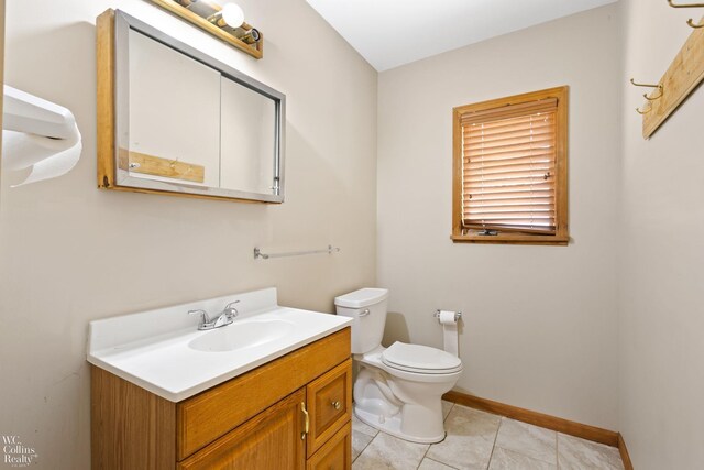 half bathroom featuring vanity, toilet, tile patterned flooring, and baseboards