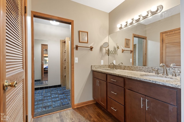 full bath featuring a closet, a sink, double vanity, and wood finished floors