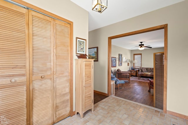 corridor with baseboards, a notable chandelier, and brick floor