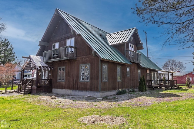 view of property exterior featuring a standing seam roof, a yard, a balcony, and metal roof