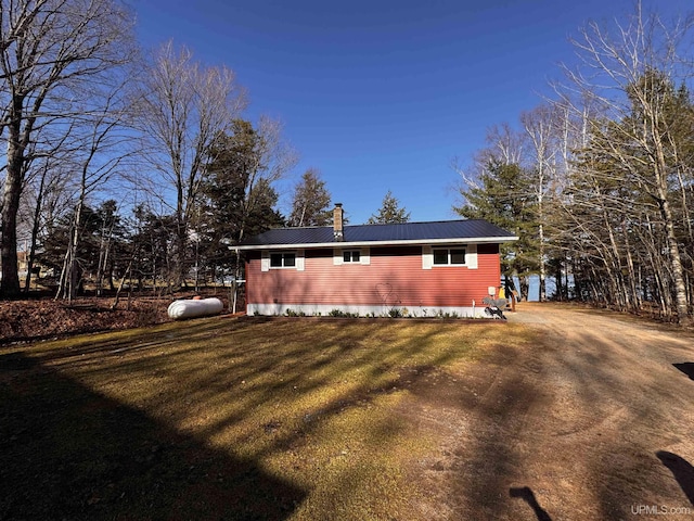 view of home's exterior featuring metal roof, a lawn, and a chimney