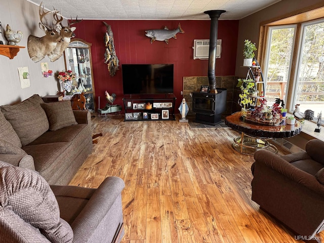 living area featuring hardwood / wood-style floors, a wood stove, and a wall mounted air conditioner
