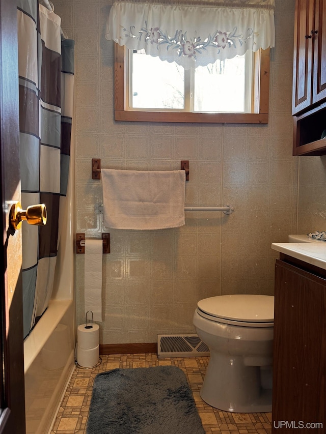 bathroom with visible vents, toilet, vanity, and shower / tub combo with curtain