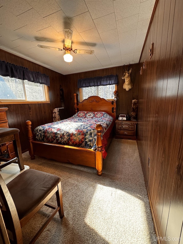 bedroom with a ceiling fan, wooden walls, and carpet floors