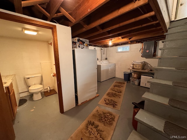 below grade area featuring washing machine and dryer, stairs, electric panel, and freestanding refrigerator