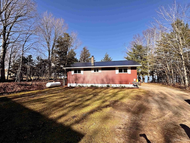 exterior space with a chimney, metal roof, and a yard