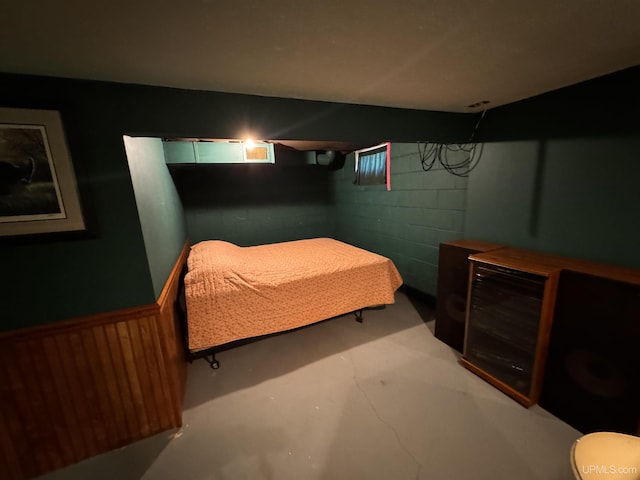 bedroom featuring concrete block wall and concrete flooring