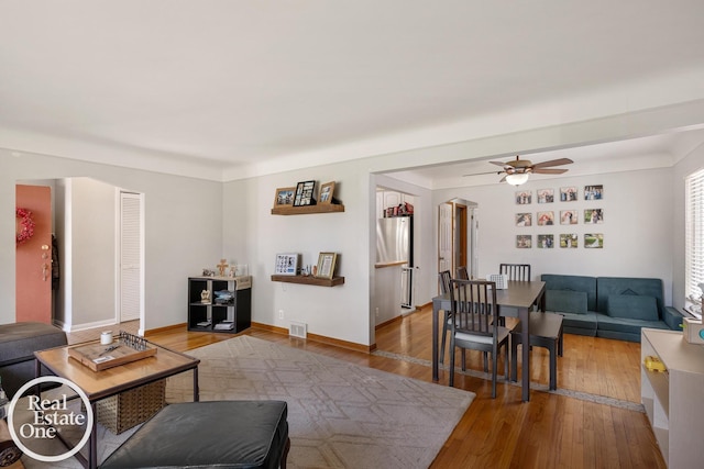 living area with visible vents, ceiling fan, baseboards, and light wood-style floors