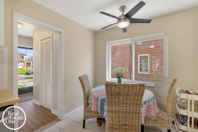 dining space with light tile patterned flooring, a ceiling fan, and baseboards