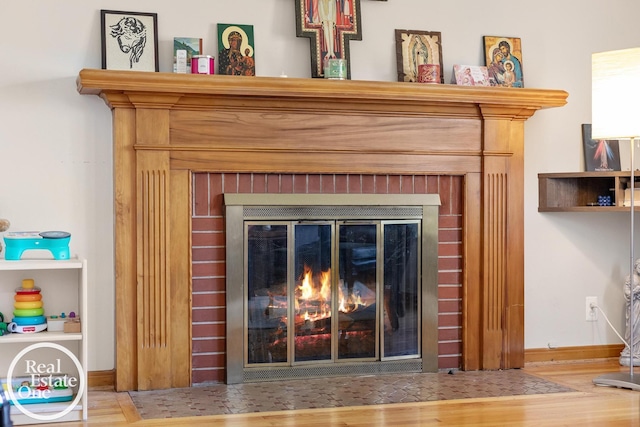interior details with a fireplace, wood finished floors, and baseboards
